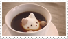 a stamp with a filled teacup with a ceramic cat inside it